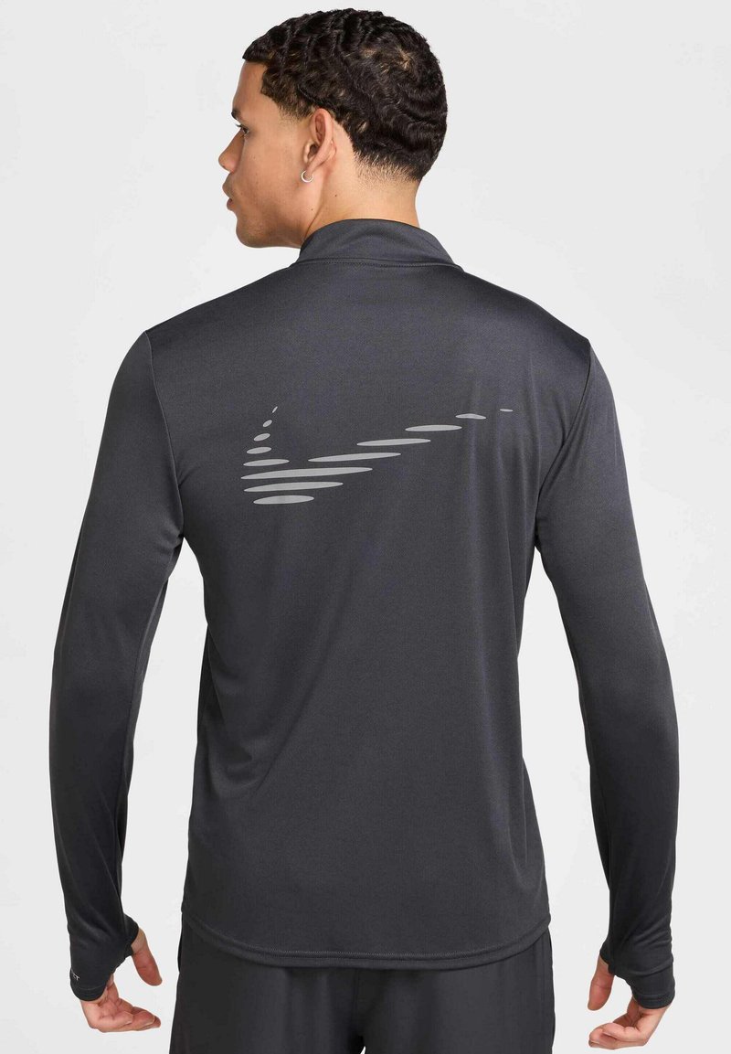 Langärmeliges Sportoberteil in Dunkelgrau, mit einem reflektierenden Nike-Logo auf der Rückseite, aus glattem, leichtem Material gefertigt.