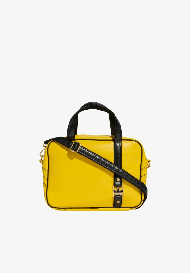 Sac rectangulaire jaune avec poignées noires et bandoulière noire réglable, avec une petite boucle de logo argentée à l'avant.