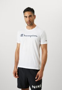 Witte katoenen t-shirt met een blauwe "Champion" logo over de borst, met een klassieke ronde hals en korte mouwen.