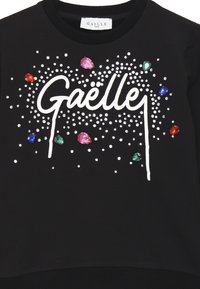 Felpa nera con grafica bianca "Gaëlle", decorata con accenti di gemme colorate e dettagli in borchie argento. Collo rotondo standard.