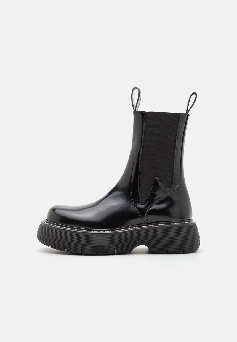 Black leather ankle boot with elastic side panels, rounded toe, and thick rubber sole. Features pull tabs for easy wear.