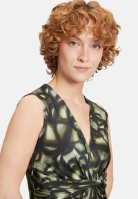 Ärmelloses Kleid in Schwarz und Grün mit einem wirbelnden Muster, ausgestattet mit einem tiefen V-Ausschnitt und einem geknoteten Taillendetail für zusätzlichen Textur.