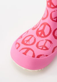 Ροζ αδιάβροχο μπότες με σχέδιο από κόκκινους συμβόλους ειρήνης, υφασμάτινη ροζ σόλα και λείο άνω μέρος με στρογγυλή μύτη.