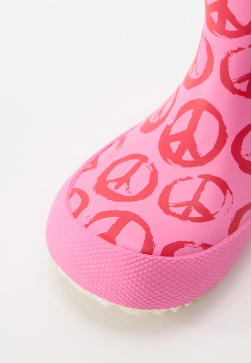 Rosa Gummistiefel mit einem Muster aus roten Friedenssymbolen, strukturiertem rosa Absatz und glattem Obermaterial mit abgerundeter Zehenform.