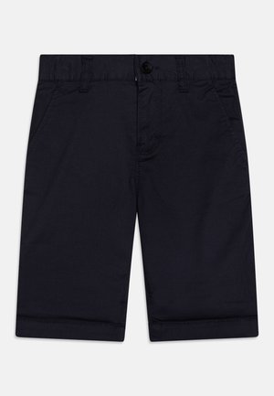 Pantaloni corti in cotone blu navy con chiusura a bottone, due tasche laterali e orli arrotolati. La texture liscia e il design pulito enfatizzano la funzionalità.