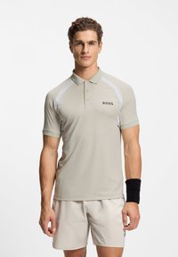 Light beige polo shirt with short sleeves, a collar, and white accents. Features "BOSS" logo on the left chest. Smooth texture.
