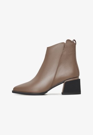 Bruine enkellaars met puntige neus, getextureerde achterkant, lus om aan te trekken en zwarte blokhak.