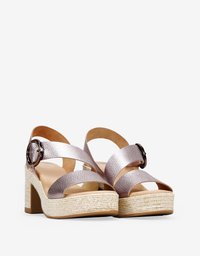 Sandalias de plataforma con un tacón grueso, que presentan tiras cruzadas en metal color rosa dorado y una hebilla decorativa de hardware. Base texturizada de cuerda.
