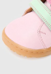 Pantof roz din piele cu talpă de cauciuc, prevăzut cu o curea cu velcro în verde mentă și detalii texturate de cusături. Design cu vârf rotund.