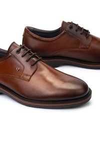 Chaussures habillées en cuir brun avec une finition lisse, bout rond, design à lacets et marquage subtil sur le côté. Semelle en caoutchouc noir avec des accents orange.