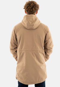 Parka beige leggera con cappuccio, caratterizzata da una vestibilità comoda e una vita elastica. Texture liscia, design lungo fino al ginocchio.