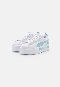 White platform sneakers with light blue accents, smooth synthetic material, textured side panels, and flat laces. Rounded toe design.