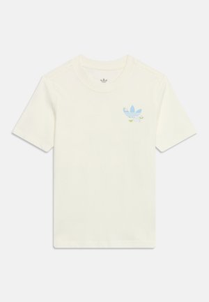 Kremowa koszulka z krótkim rękawem, okrągłym dekoltem i niebieskim logo Adidas trefoil z kwiatowymi akcentami na lewej piersi.