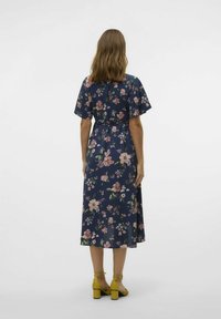 Robe maxi florale avec manches courtes, fond marine et fleurs roses. Comprend une taille à nouer, une silhouette fluide et un ourlet juste au-dessus de la cheville.