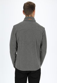 Gray fleece jacket featuring a high collar and subtle stitching details. The back displays an orange logo near the neck.