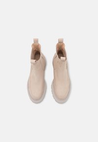 Bottines beiges en daim, avec une surface lisse, un bout arrondi, une languette au talon et des coutures de semelle contrastantes.