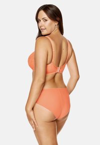 Koronkowy zestaw bielizny w kolorze koralowym składający się z biustonosza z regulowanymi ramiączkami oraz pasujących majtek o wysokim stanie. Gładka tekstura z subtelnym połyskiem.