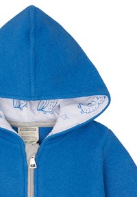 Giacca a vento blu in lana con fodera grigia, presentante un interno di tessuto bianco stampato con motivi di gufo blu e una cerniera argentata.