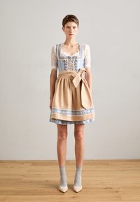 Traditionelles Kleid mit einem Spitzenoberteil, in hellblau und beige, mit gebundenem Taillenbereich und gemustertem Rocksaum. Getragen mit grauen Socken und Schuhen mit Absätzen.