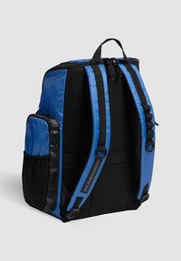 Mochila azul y negra con una superficie texturizada, correas ajustables, bolsillo lateral con cremallera y un asa superior. Presenta un diseño elegante y moderno.