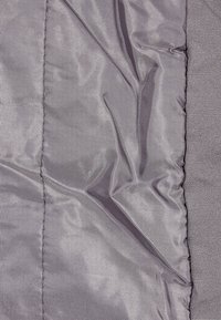 Tessuto in nylon grigio con una finitura testurizzata, caratterizzato da un design stropicciato e cuciture visibili; superficie complessivamente liscia con una leggera lucentezza.