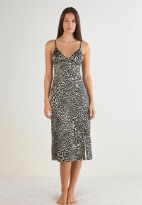 Zwarte en beige luipaardprint slipdress met dunne verstelbare bandjes, een V-hals en een zijsplit, gemaakt van een zachte, lichte stof.