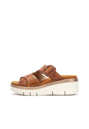 Sandalia de cuero marrón sin cierre con correa ajustable con hebilla, plantilla acolchada y suela plataforma blanca texturizada.