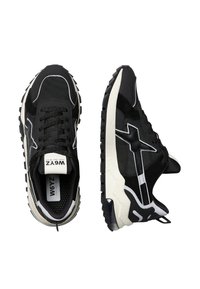 Schwarze Sportsneaker aus Textil und Wildleder, mit weißen Akzenten, einer dicken Gummisohle und runden Schnürsenkeln. Mit einem auffälligen Logo.