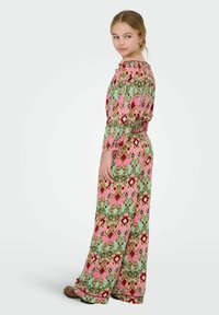 Maxi šaty v zelené, růžové a červené barvě s složitými geometrickými a květinovými vzory. Mají smockovaný výstřih a dlouhé rukávy.