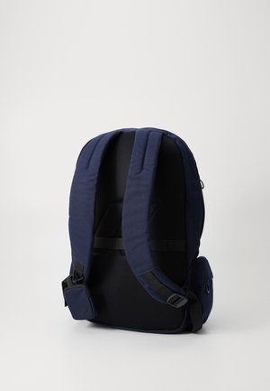 Mochila navy con espalda de malla acolchada, correas de hombro ajustables y un bolsillo lateral. Tela resistente, diseño elegante y hardware discreto.