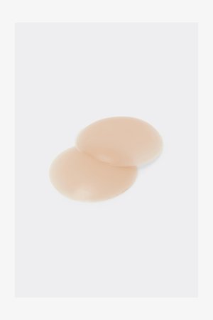 Nude silikonowe nakładki w kształcie okręgu o gładkiej fakturze, zaprojektowane do dyskretnego zakrycia, z miękkiego, elastycznego materiału.