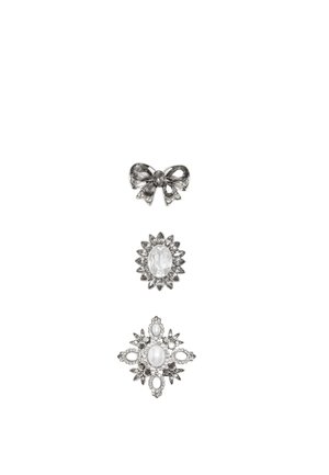 Trois broches en argent et pierres précieuses transparentes : en forme de nœud en haut, rayons de soleil ovales au milieu, diamant en bas avec des détails en perle et cristal.