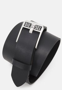 Ceinture en cuir noir avec une boucle en métal argenté portant le nom de la marque "DIESEL". Texture lisse avec une forme rectangulaire et une pointe effilée.