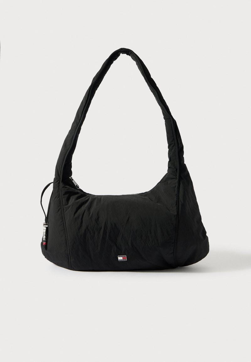 Fekete nylon válltáska ívelt fogantyúval, cipzáras zsebbel és kis logóval az elején; pufi textúrájú, puha, lekerekített formájú.
