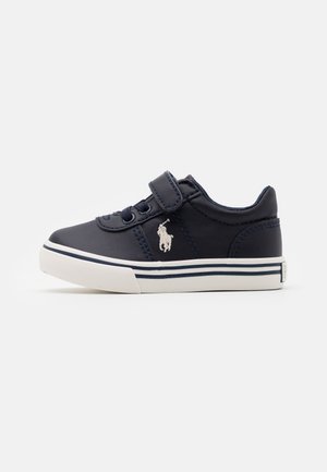 Marineblå sneaker til småbørn med hvid sål, velcrolukning, snørebånd og hvidt logo med en hest og rytter på siden.