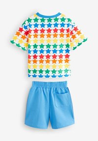 Camiseta de manga corta con un patrón de estrellas multicolores en rojo, azul, amarillo y verde; combinada con pantalones cortos azul claro que cuentan con un bolsillo trasero.