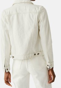Witte spijkerjasje met een getailleerd ontwerp, gebuttonede manchetten en verstelbare zijtabjes. De stof heeft een gladde textuur en subtiele stikdetails.