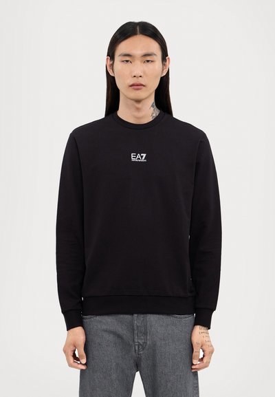 Sweatshirt noir en mélange de coton avec col ras du cou, poignets et ourlet côtelés. Présente un petit logo EA7 blanc sur la poitrine. Texture lisse.