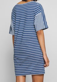 Vestido de manga corta a rayas azul y blancas, hecho de una tela suave, presenta un corte relajado y un escote redondeado. La vista trasera muestra detalles de costura.