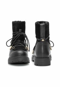 Czarne botki do kostki wykonane z połączenia gładkiej skóry i miękkiego zamszu, z akcentami w postaci złotych elementów ozdobnych oraz teksturowanymi gumowymi podeszwami zapewniającymi przyczepność.