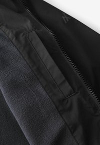 Intérieur de veste en polaire noire avec un panneau en nylon noir doté d'une fermeture éclair et d'un détail élégant de poche plaquée pour un rangement sécurisé.