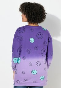 Paarse trui met zwarte en turquoise smiley-gezicht patronen, met een verloop effect dat vervaagt van donker naar lichter paars.