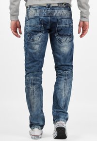 Jeans in denim con una lavatura blu sbiadita e un design aderente. Le caratteristiche includono tasche posteriori, dettagli di cucitura e una vita texturizzata.