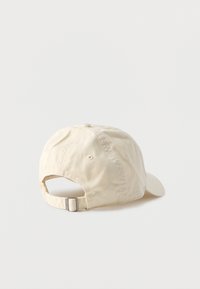 Μπεζ βαμβακερό καπέλο μπέιζμπολ, εμφανιζόμενο από πίσω, με ρυθμιζόμενο λουράκι και μεταλλικό πόρπη σε απλό λευκό φόντο.