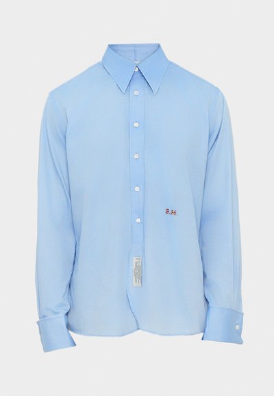 Lichtblauw langärmelig shirt met een brede kraag, knopen aan de voorkant en geborduurde initialen "B.M." aan de linkerkant. Labels zichtbaar aan de onderkant.