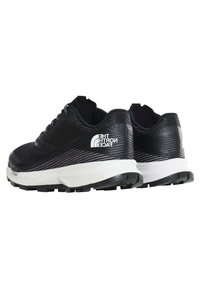 Paire de chaussures de trail The North Face basses en noir et blanc avec dessus texturé et semelles extérieures robustes.