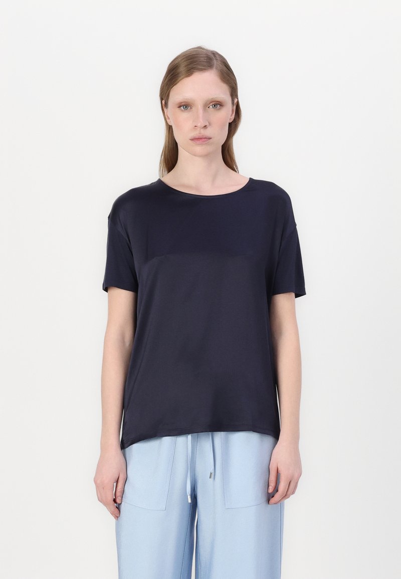 T-shirt a maniche corte blu navy in tessuto morbido, scollo rotondo, vestibilità rilassata, texture liscia, abbinato a pantaloni azzurri chiari con tasche.