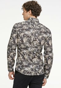 Langarmshirt met een zwart, wit en beige bladerenpatroon op een lichtgewicht stof. Met kraag en knoopsluiting bij de manchetten.