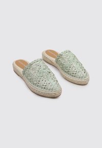 Zapatos de crochet verdes tipo slip-on con patrones florales, suela de yute y puntera redondeada. Diseño ligero adecuado para climas cálidos.