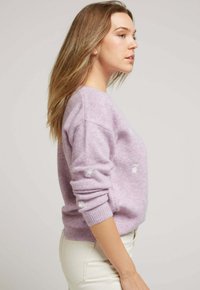 Pull violet en matériau doux, avec un col rond et des poignets côtelés, orné de subtils détails brodés en blanc.
